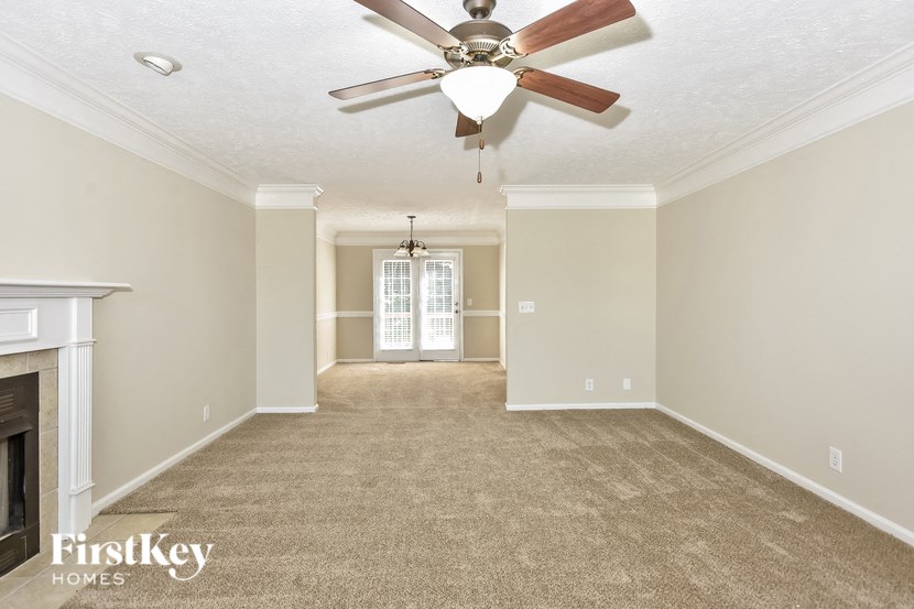 an empty living room with a ceiling fan and a fireplace
