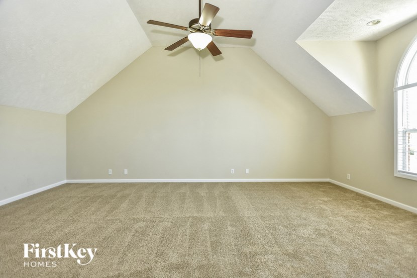 the bonus room has a ceiling fan and a carpeted floor