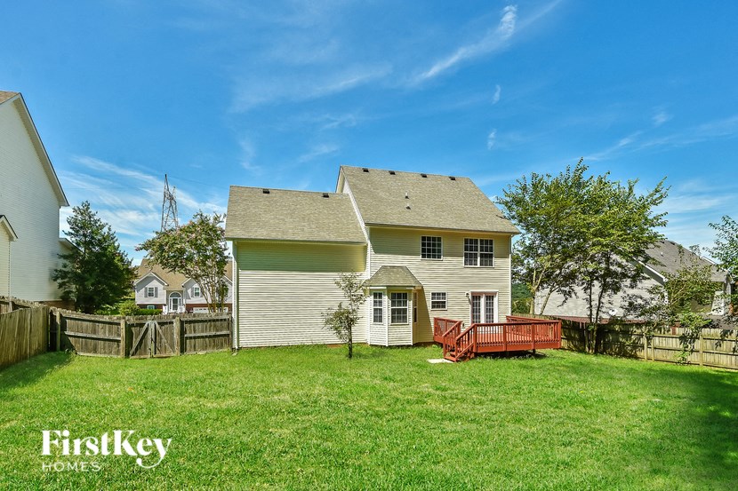 a backyard with a white house and a wooden fence