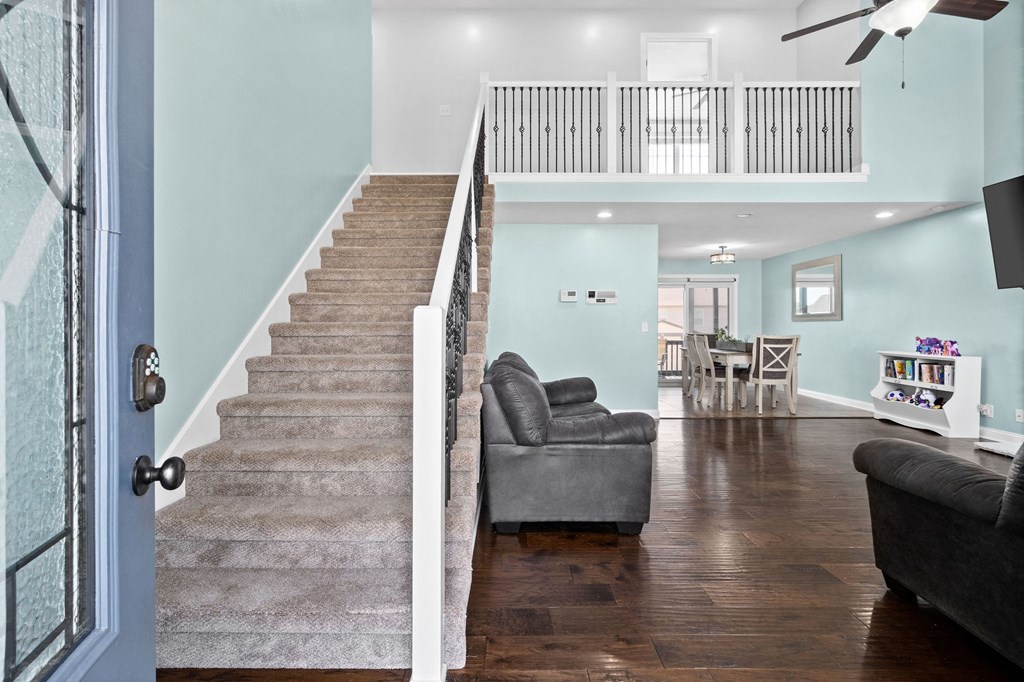 a living room with a staircase and a couch    and a dining room