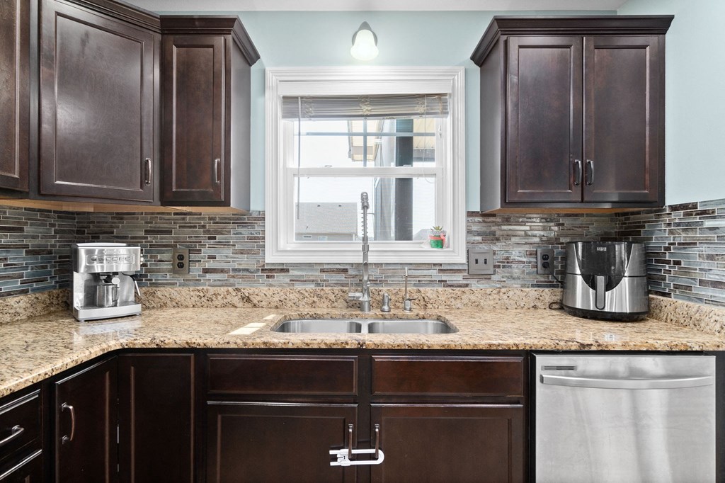 a kitchen with brown cabinets and a sink and a window