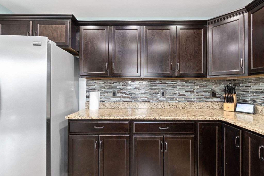 a kitchen with brown cabinets and a stainless steel refrigerator