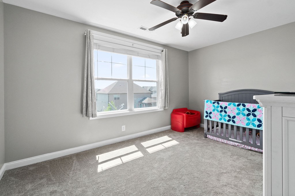 a nursery with a crib and a ceiling fan