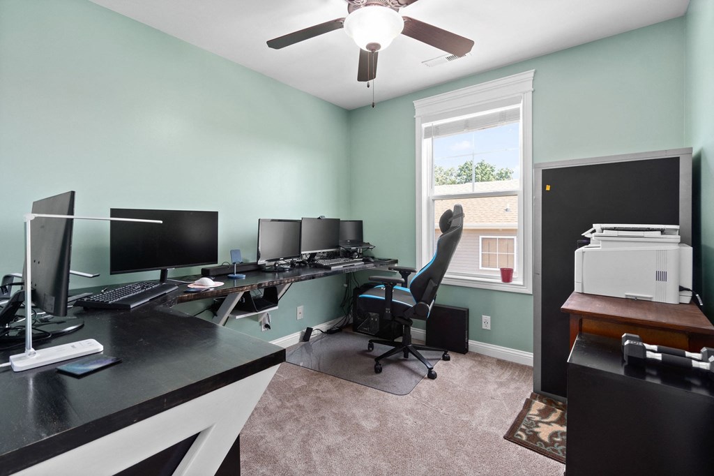 a home office with two computer desks and a window