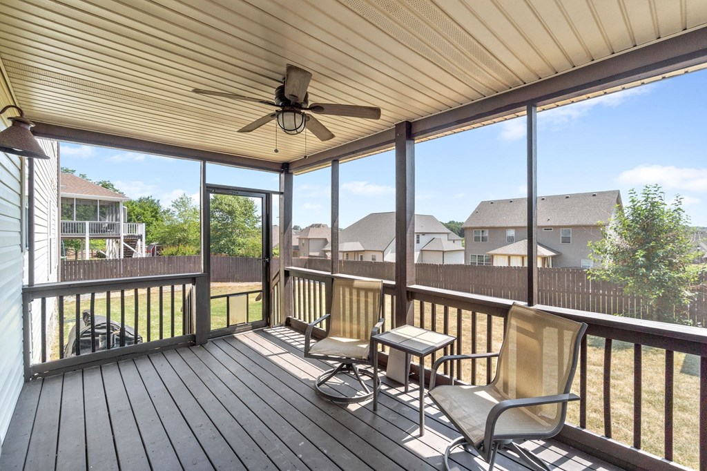 a covered porch with two chairs and a ceiling fan