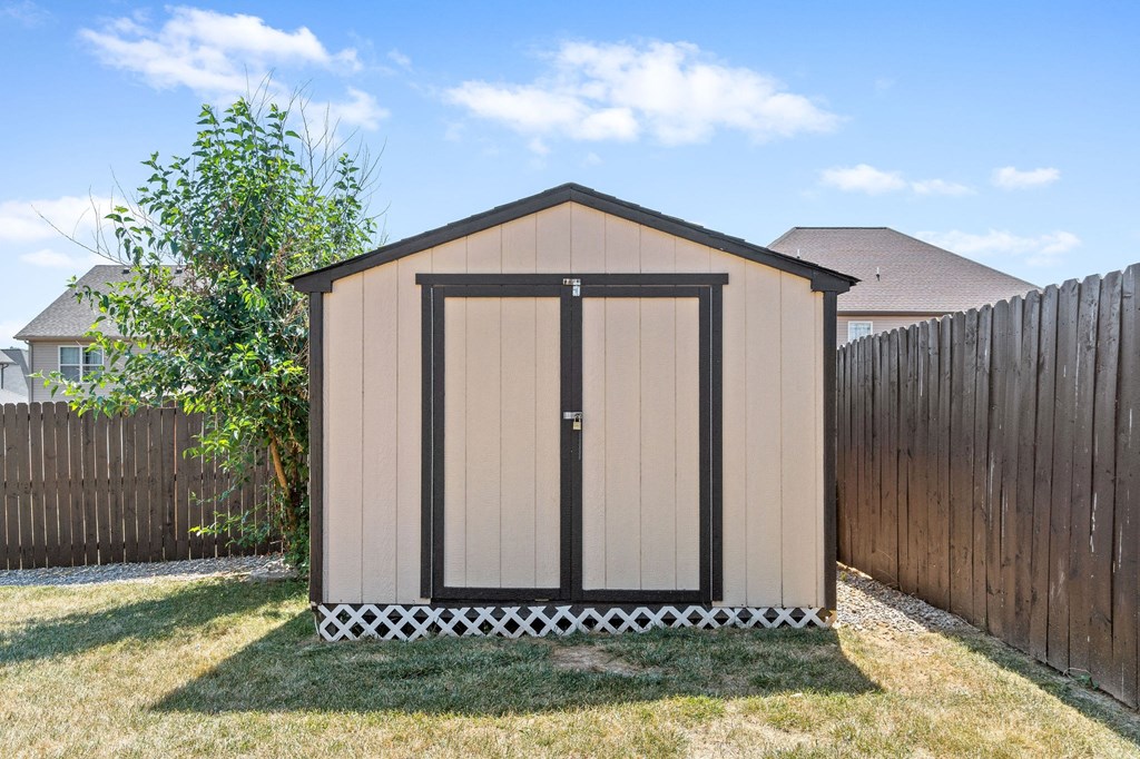 a small backyard shed with a fence and grass