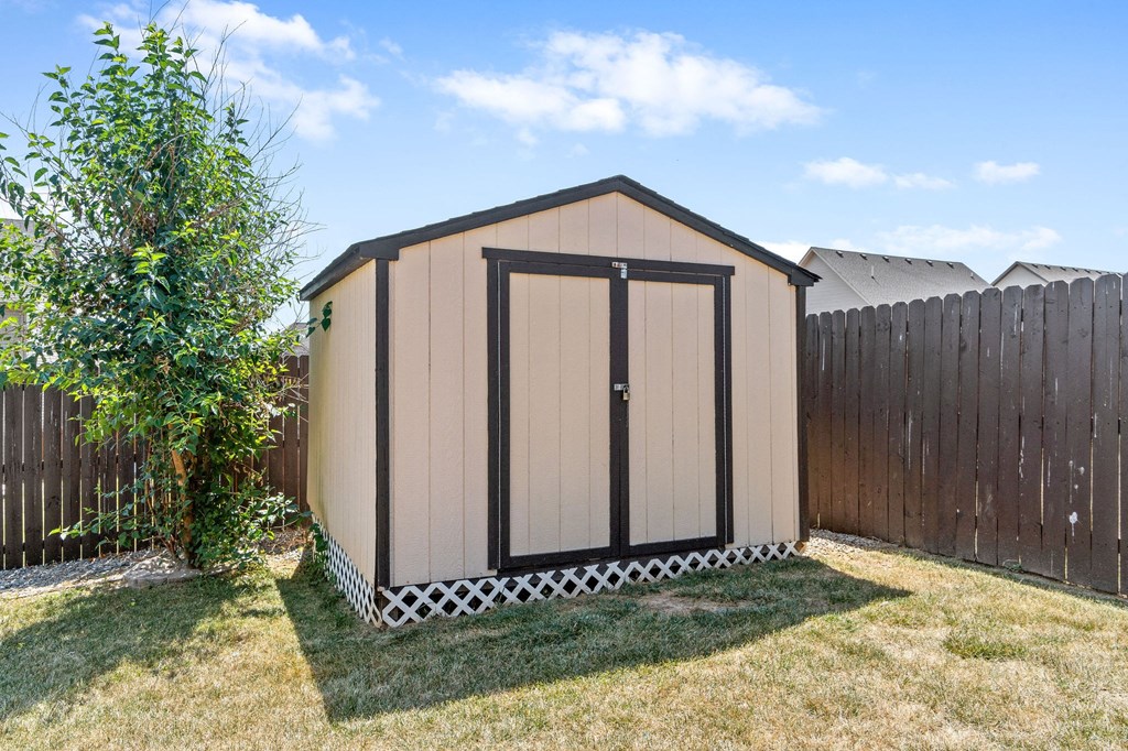 a small shed in a backyard with a fence and a tree