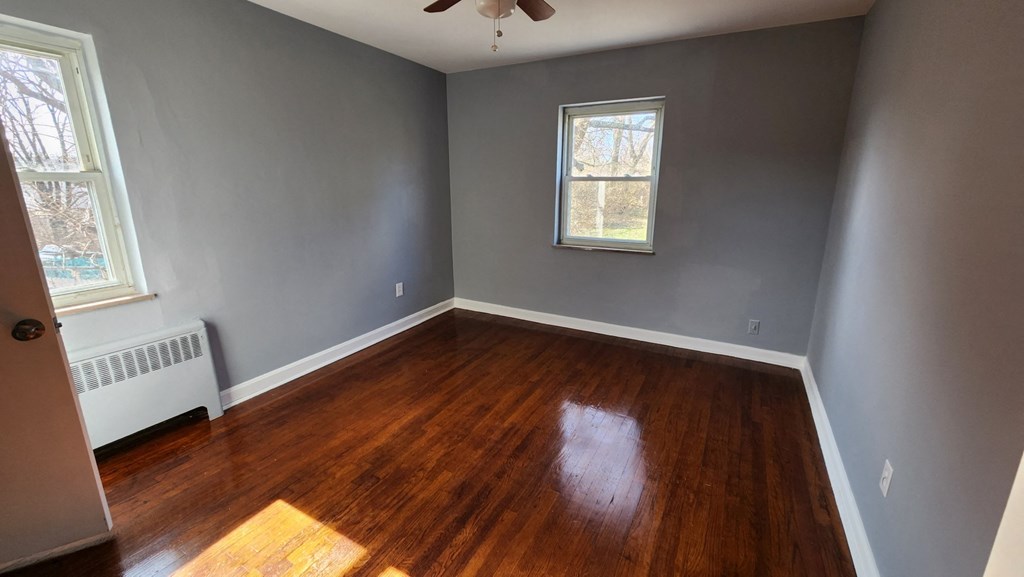 an empty room with wooden floors and grey walls and a window