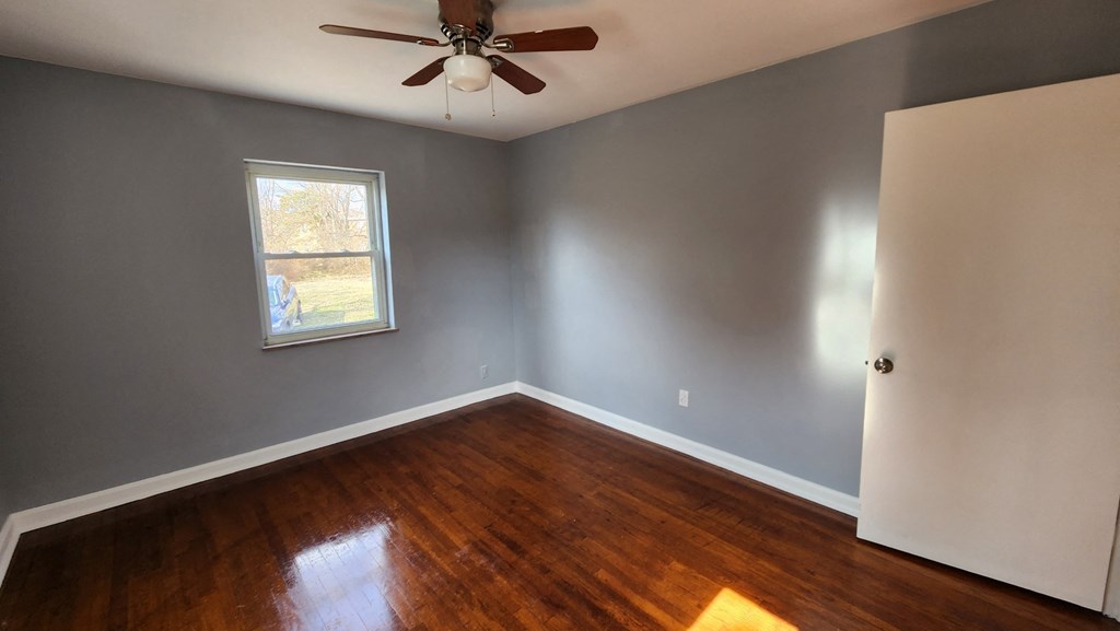 an empty bedroom with wooden floors and a ceiling fan