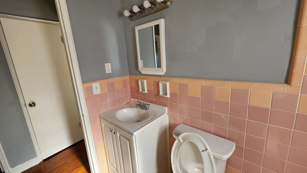 a bathroom with pink tile and a sink and a toilet