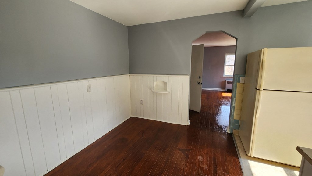 an empty room with a refrigerator and a hard wood floor