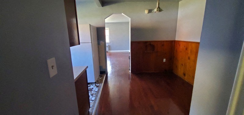 a living room with a wooden floor and a hallway to a bedroom