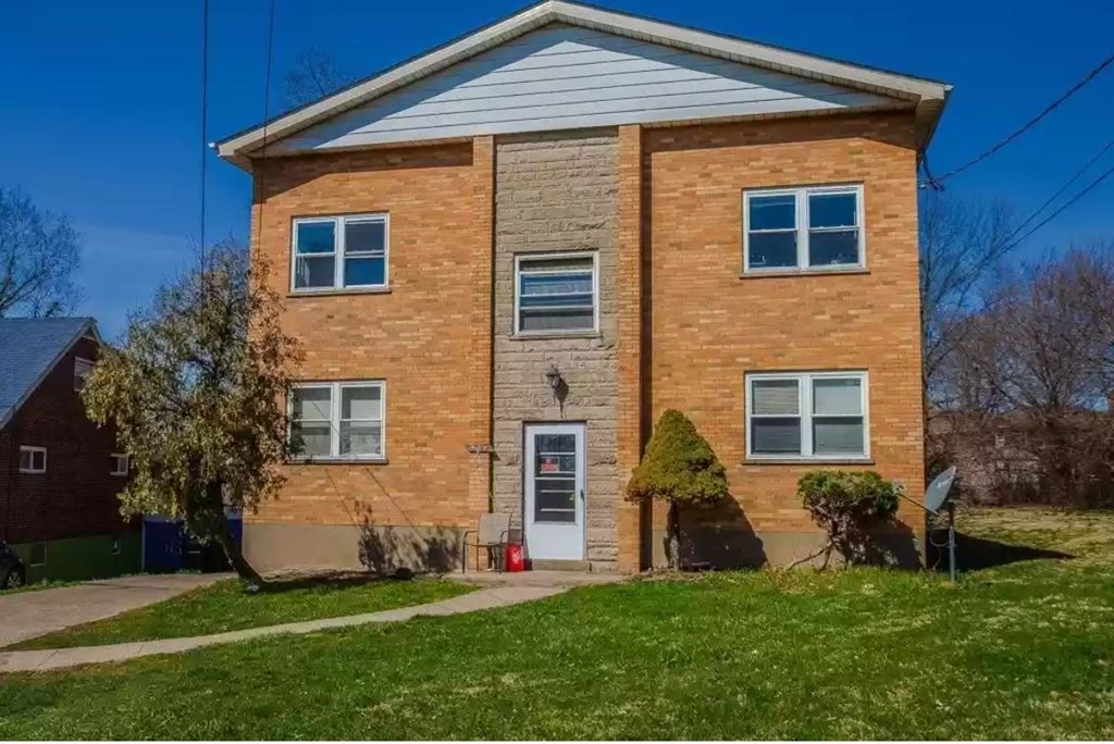 a brick house with a white roof and a green lawn