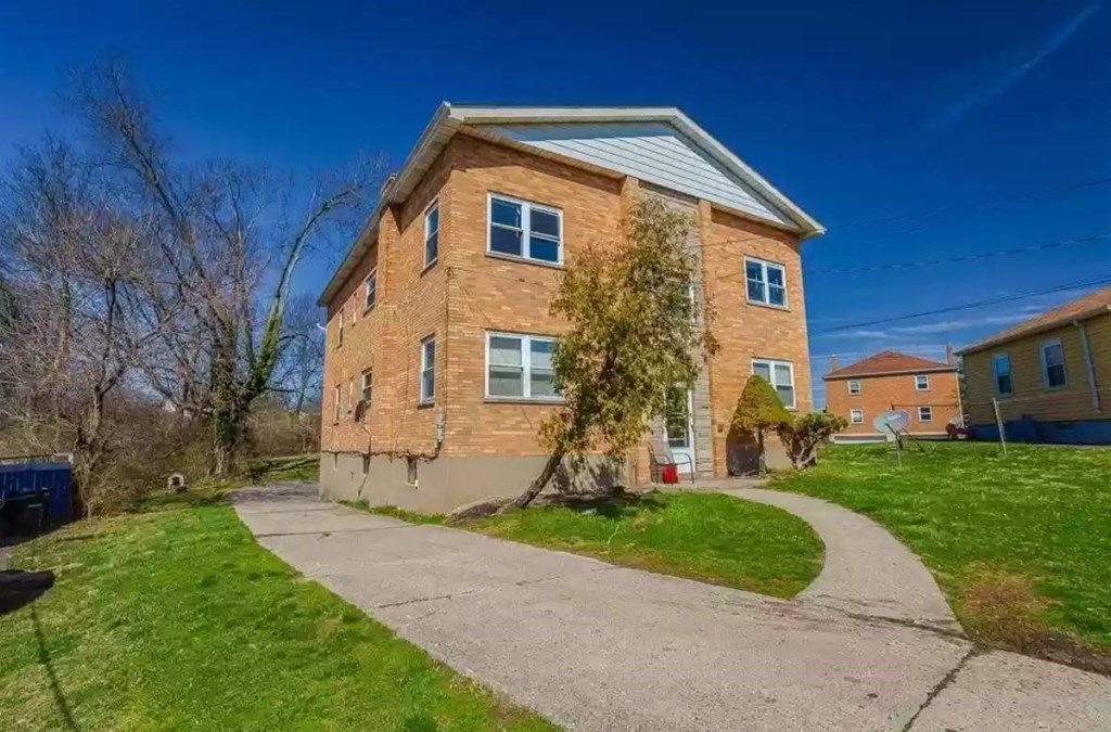 a brick house with a sidewalk in front of it