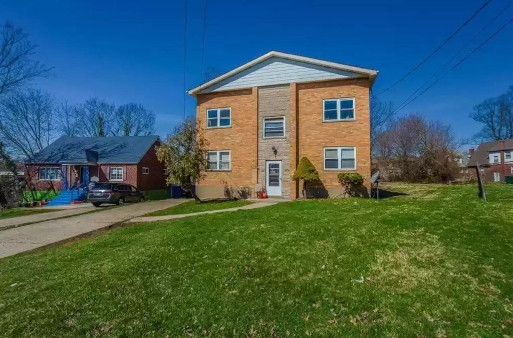 a brick house with a green lawn in front of it