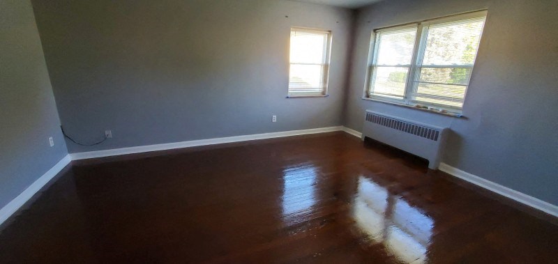 a empty room with a wooden floor and two windows