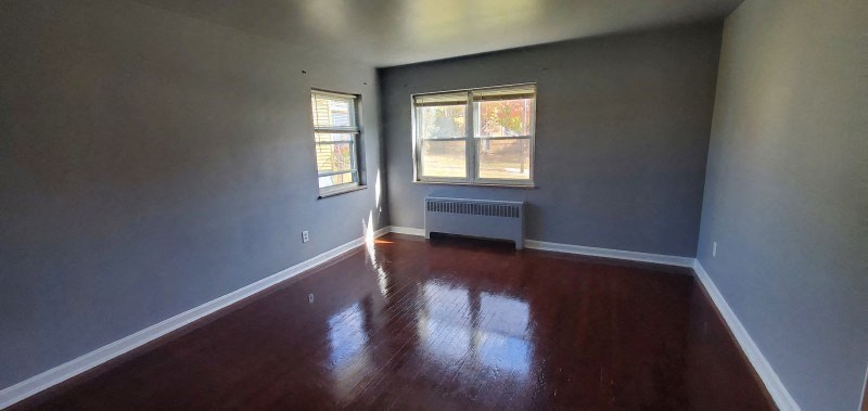 an empty living room with wooden floors and a window