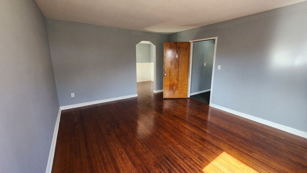 an empty living room with wooden floors and a wooden door