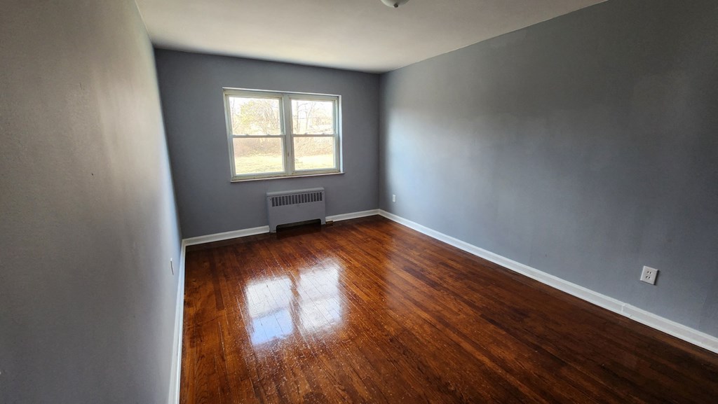 an empty room with wooden floors and a window