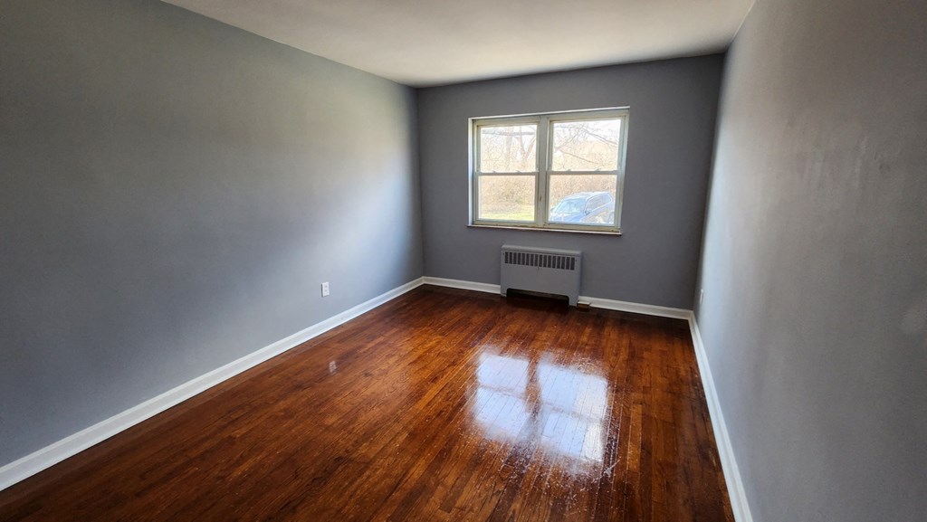 an empty room with wooden floors and a window