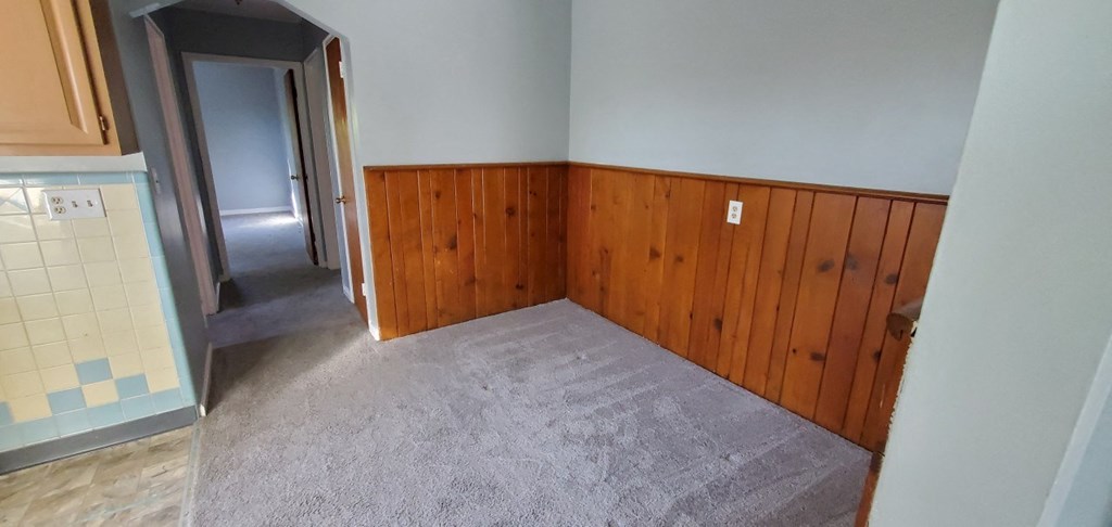 an empty room with wood paneling and a carpet floor