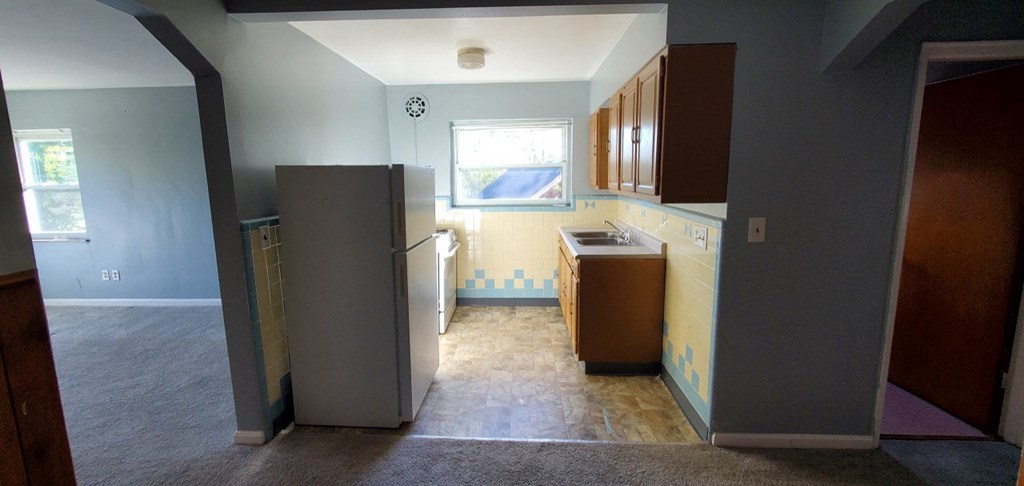 an empty kitchen with a refrigerator and cabinets
