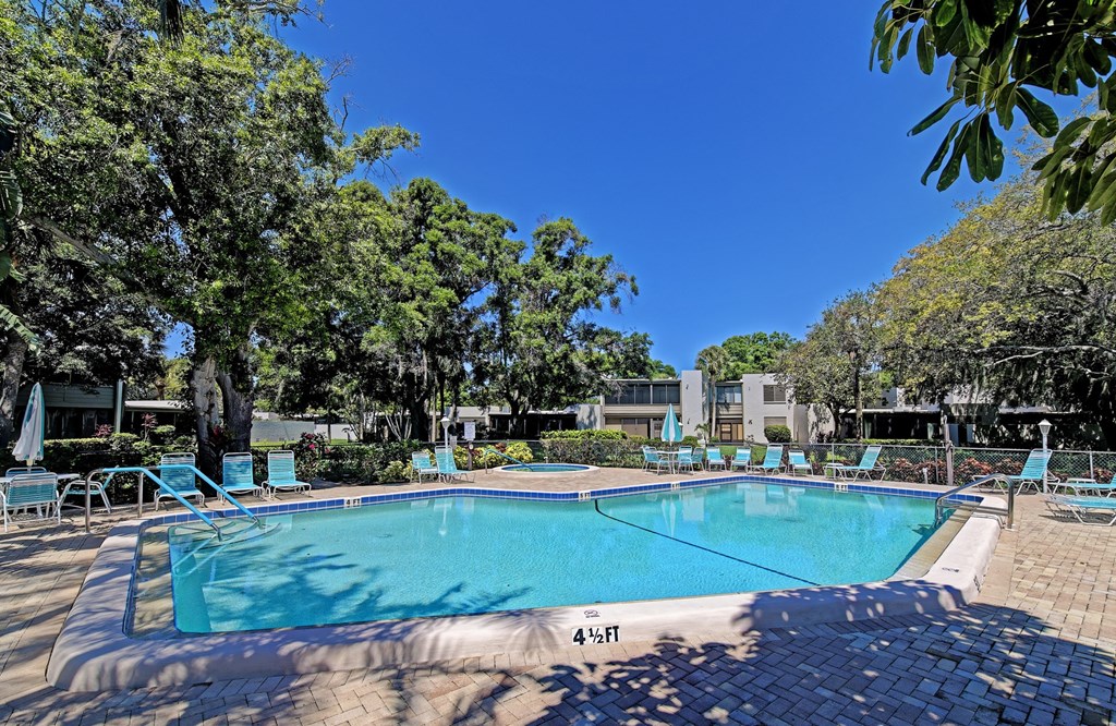 a swimming pool with blue chairs around it and trees