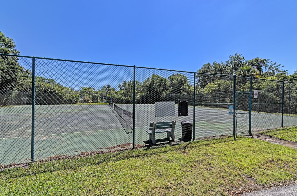 a tennis court with a bench in front of a fence