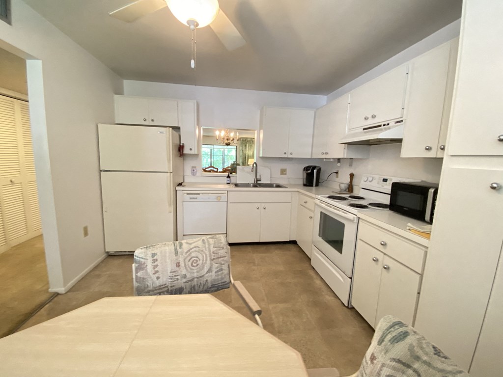 a kitchen with white cabinets and appliances and a table