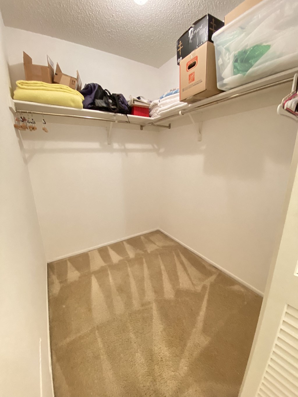 a walk in closet with a beige floor and shelves