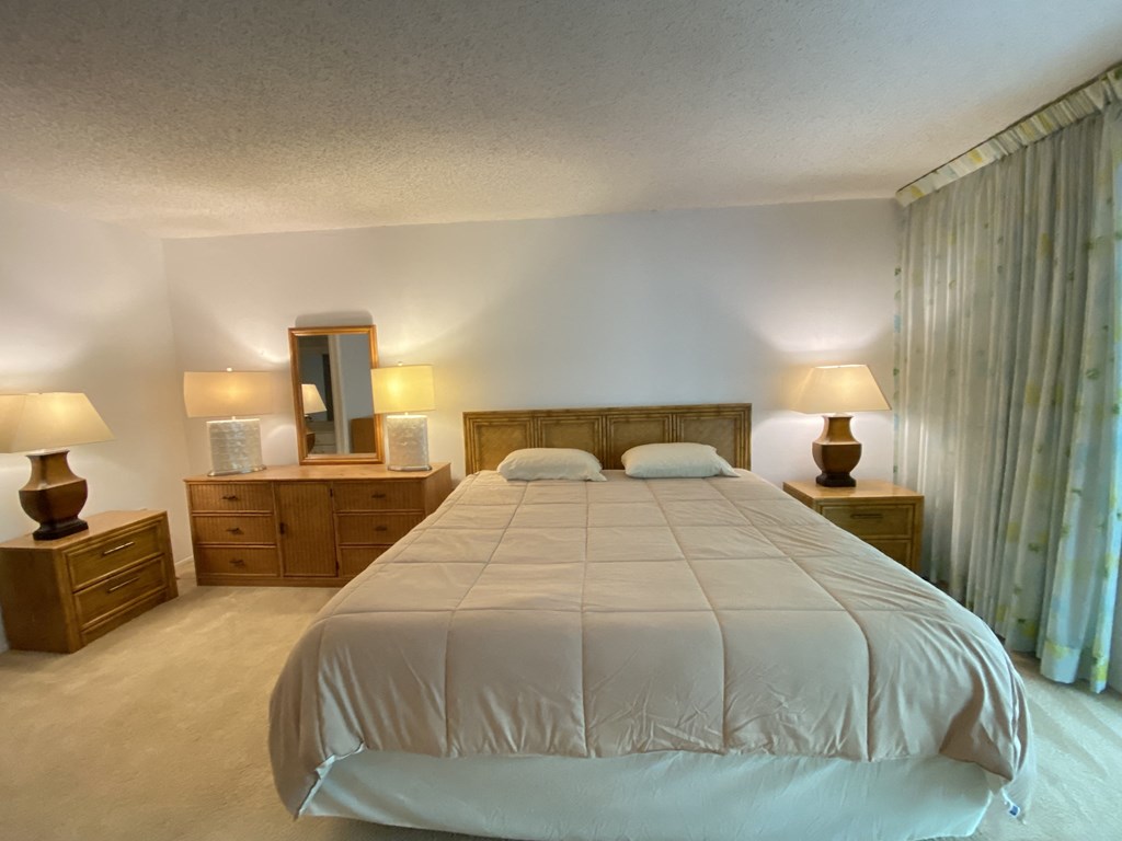 a bedroom with a bed and dressers and a window