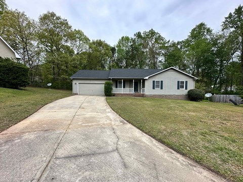a small white house with a driveway and a lawn