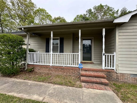 the front of a house with a porch and a white fence