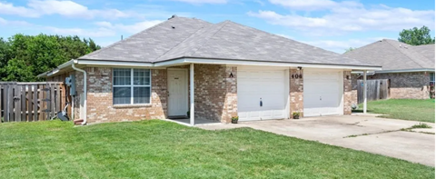 a small brick house with two white garage doors