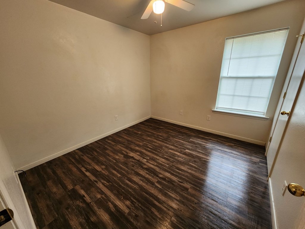 an empty living room with wooden floors and a window