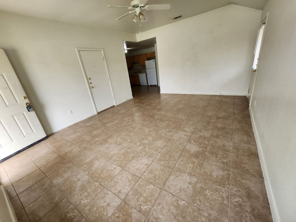 an empty living room with tile floors and a ceiling fan