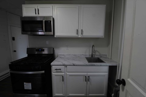 A kitchen with white cabinets and a black stove top oven.