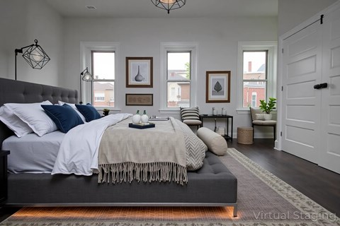 A bedroom with a large bed and a grey headboard.