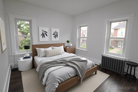 A bedroom with a bed, nightstand, and two windows.