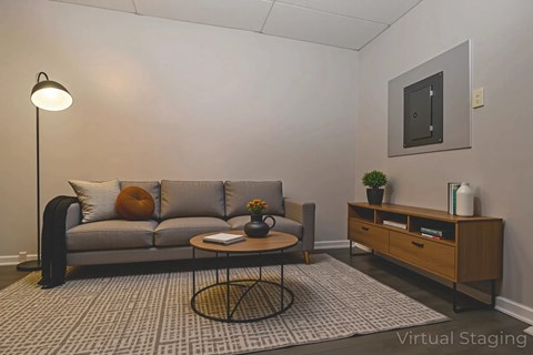 A living room with a grey couch, a coffee table, and a side table with a plant on it.