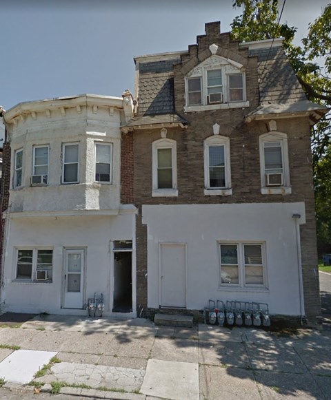 A white two-story house with a brown roof and a black door.