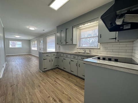 a remodeled kitchen with white cabinets and a wood floor