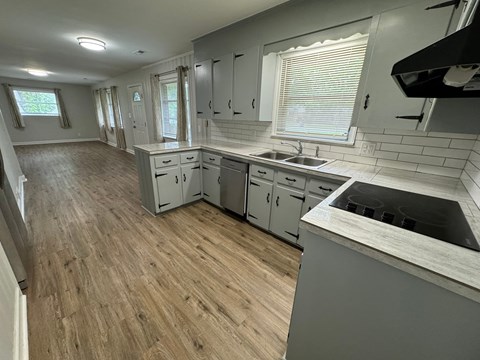 A kitchen with wooden floors and white cabinets.