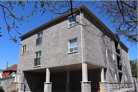 A grey stone building with a balcony and a tree branch in the foreground.