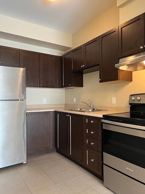 A kitchen with brown cabinets and a stainless steel refrigerator.