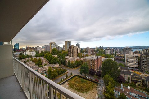 A cityscape viewed from a balcony with buildings and trees in the foreground.
