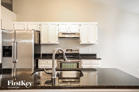 A kitchen with a stainless steel refrigerator and a stainless steel sink.