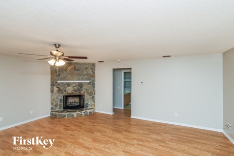 A room with a stone fireplace and wooden floors.