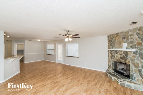 A spacious room with a stone fireplace and wooden flooring.
