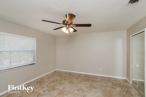 A room with a ceiling fan and a window with blinds.